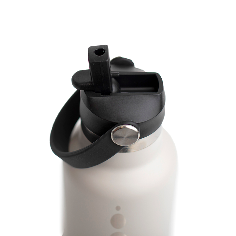 El tapón de pajita negro enroscado en una botella WaterGo en acabado Nude, con la boquilla plegada y el asa a un lado.
